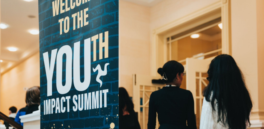 Students standing by Youth Impact Summit banner